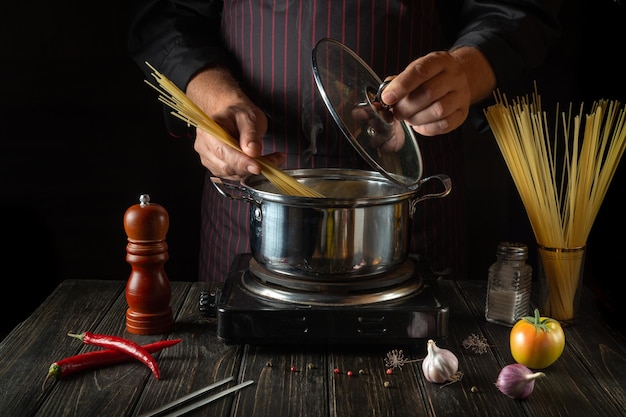 A professional chef prepares organic pasta in a pot in the kitchen