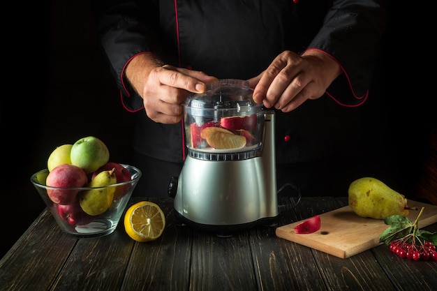 Professional chef prepares sweet fruit drink in a blender or mixer Menu or recipe idea for a healthy vegetarian breakfast or dinner