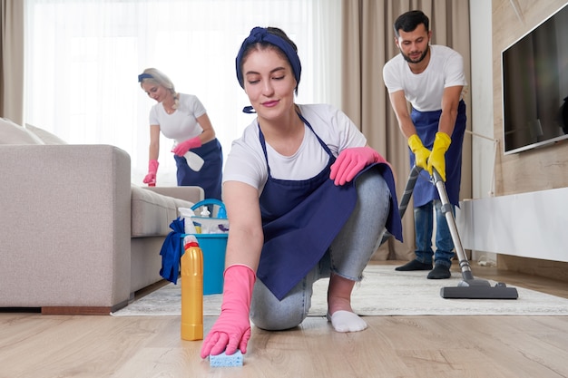 Professional cleaning service team cleans living room in modern apartment