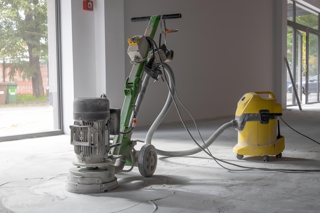 Professional concrete floor grinder vacuum cleaner connected to the grinder industrial concrete floor grinding