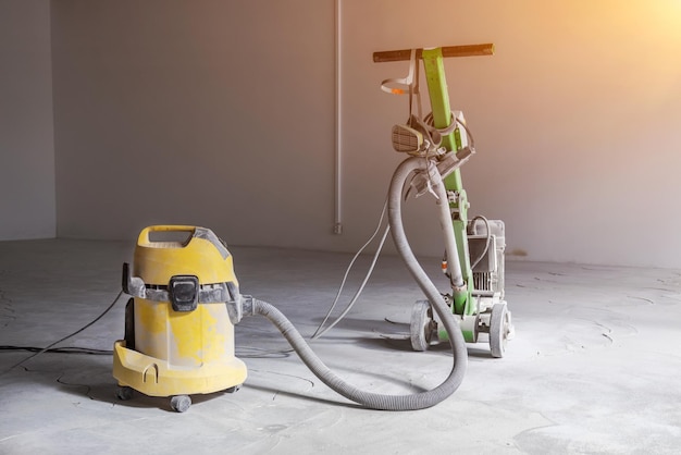 Professional concrete floor grinder vacuum cleaner connected to the grinder industrial concrete floor grinding