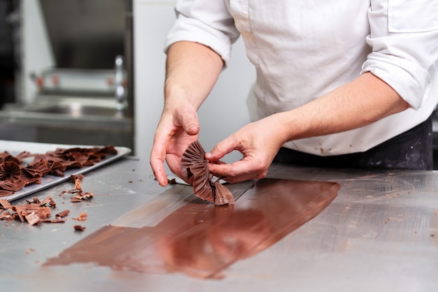 Photo professional confectioner making chocolate sweets at confectionery shop.