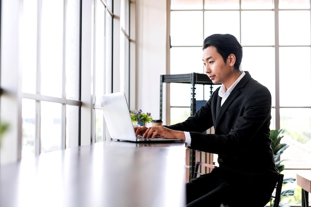 Professional confident Asian businessman smile and works on a laptop computer while online meeting businessman entrepreneur with connection and discussion skills Image with copy space