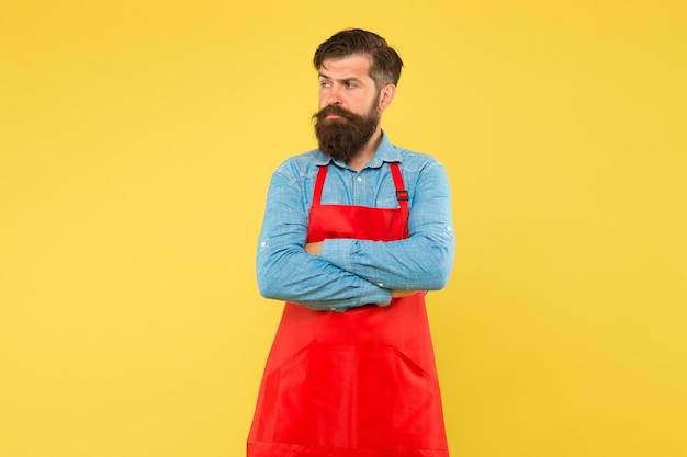 Photo professional cookery his new business guy in shop assistant uniform serious man with red apron on yellow background confident expression handsome male barista is working mature bartender