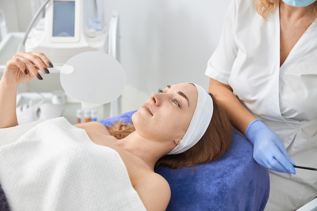 Professional cosmetologist is doing procedures for client in cabinet