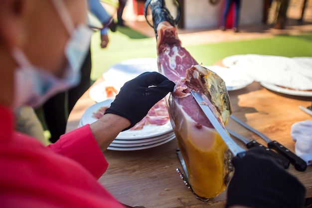 Professional cutter carving slices from a whole bonein serrano ham Spanish food