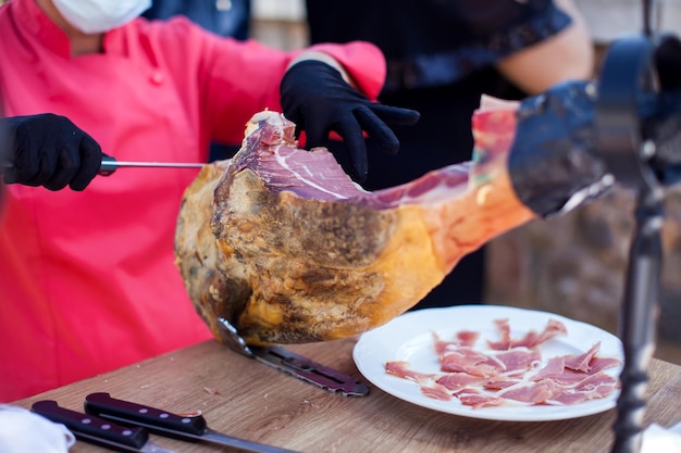 Professional cutter carving slices from a whole bonein serrano ham Spanish food