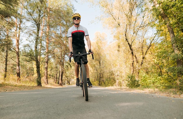 Professional cyclist trains cycling outside the city Cycling man rides on autumn forest road