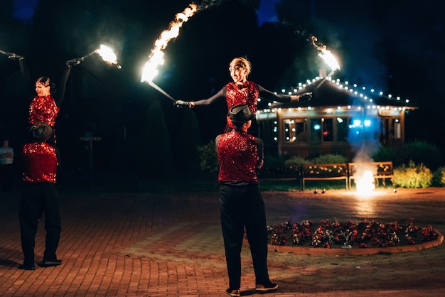 Professional dancers men and women make a fire show and pyrotechnic performance