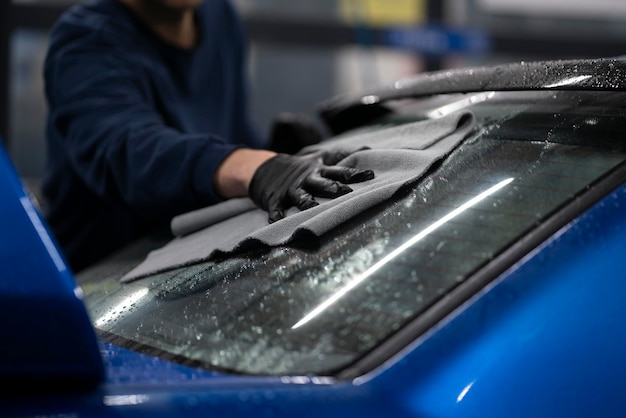 A professional detailer wiping car surface with a microfiber rag in workshop