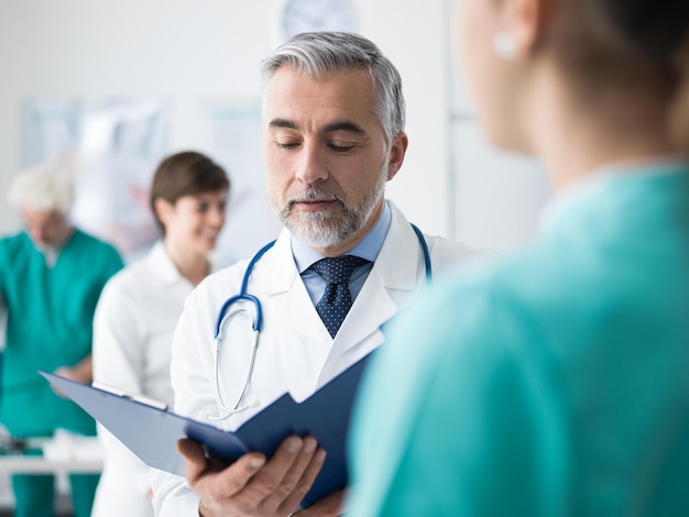 Photo professional doctor and medical staff working at the hospital he is examining patient's medical records