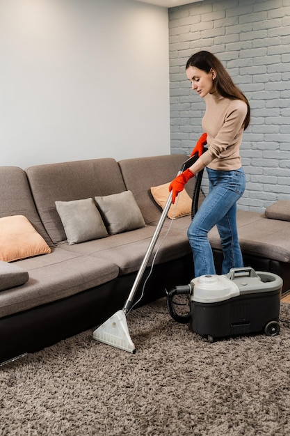 Professional domestic cleaning service worker is removing dirt and dust from carpet using dry cleaning machine mop Dry cleaning extractor mop machine is spraying water and detergent on carpet