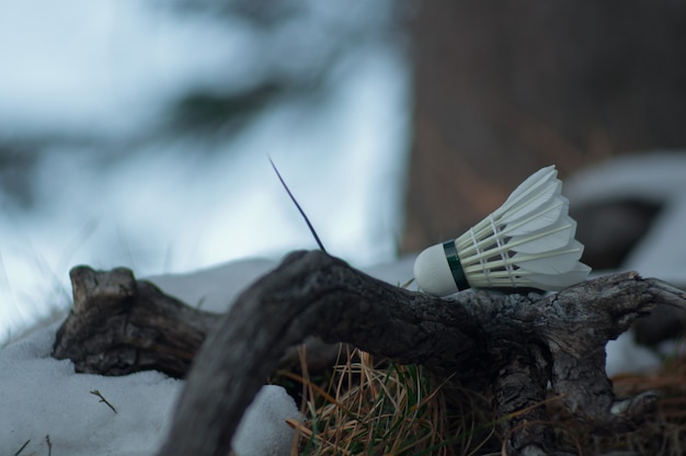 Professional feather shuttlecock for playing badminton lies outside in winter.