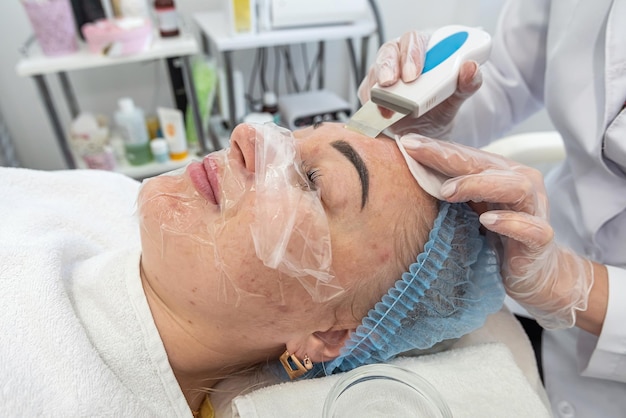 Professional female cosmetologist in a mask makes facial contour injections to female patient