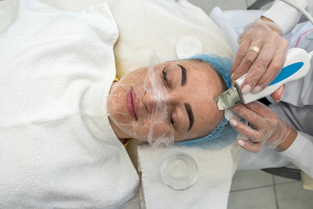 Professional female cosmetologist in a mask makes facial contour injections to female patient