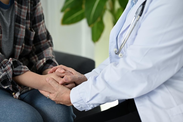 A professional female doctor holding a patient's hands giving support and reassuring