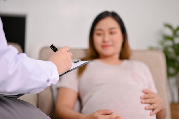 A professional female doctor writing her pregnant patient's symptoms on medical record paper