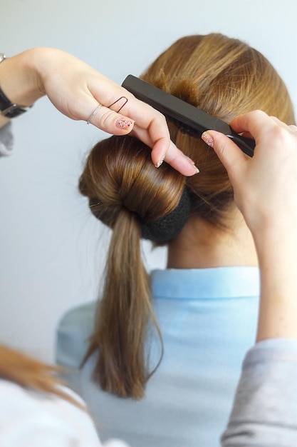 Professional female hairdresser making hairstyle to cheerful young woman with long hair