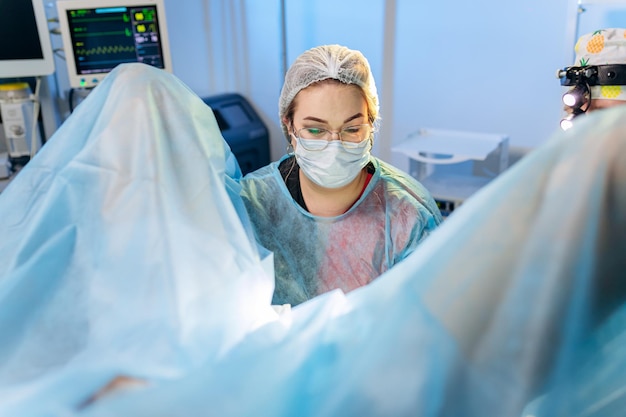 Professional female surgeon proctologist performing operation using special medical devices in the operating room in hospital Urgent surgical concept