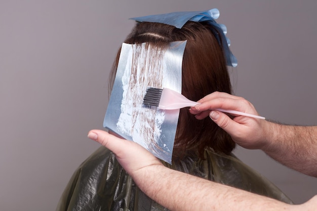 Photo professional hairdresser holding brush and dyeing hair of her client