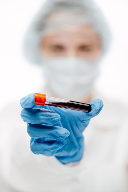 Professional lab assistant in blue glove holding glass tube of blood sample to make coronavirus test