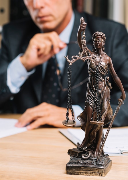 Professional lawyer sitting at the table with justice statue in forefront