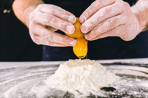 Professional male baker cooking dough with eggs