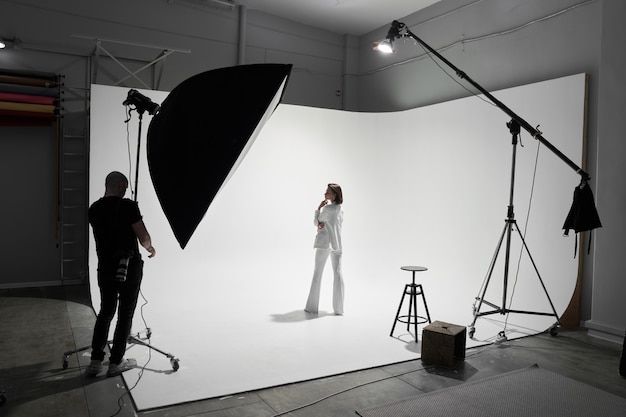 Professional male photographer taking pictures of beautiful woman model in a studio