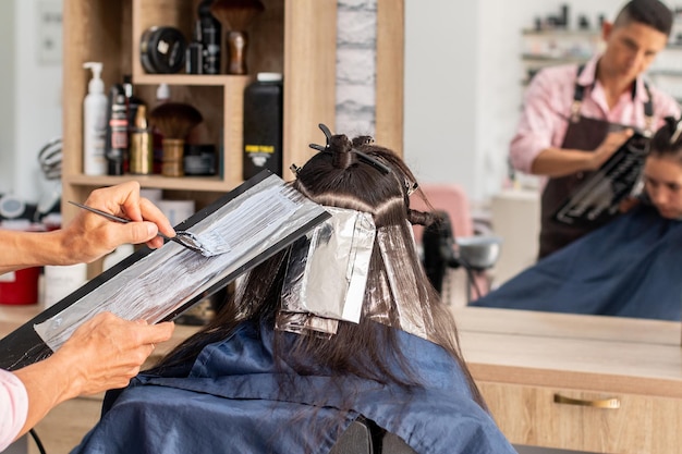 Professional male stylist painting his client's hair Professional beauty salon