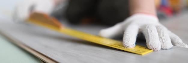 Professional male worker apply tape measure on wooden plank for further cutting