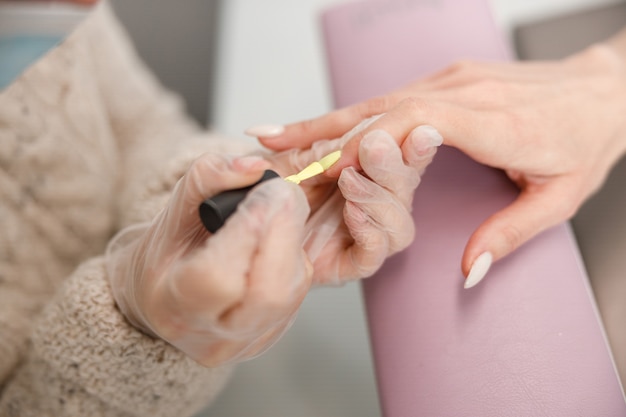 Professional manicure master doing nails for happy client in beauty salon