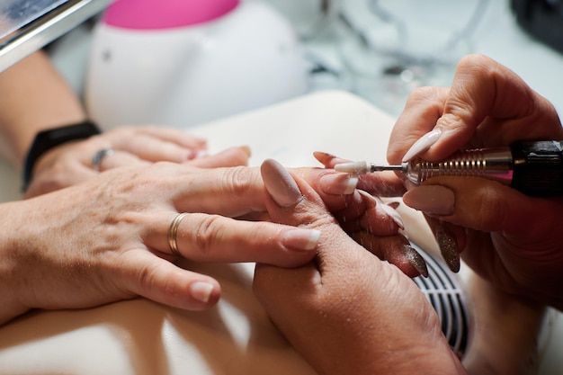 Professional manicurist fixes and beautifies a client's nails