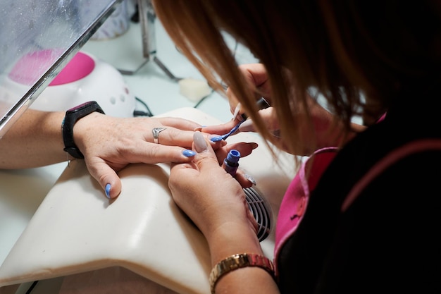 Professional manicurist fixes and beautifies a client's nails