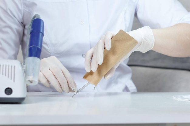 Professional manicurist opens a paper bag with sterile manicure tools