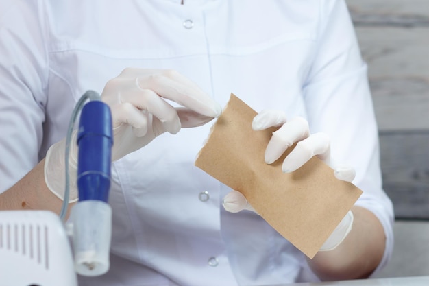 Professional manicurist opens a paper bag with sterile manicure tools