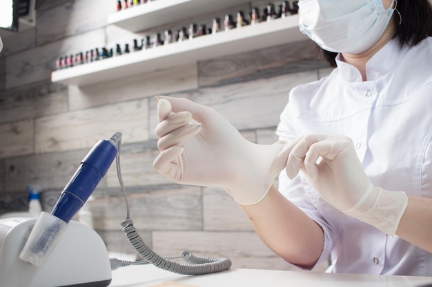 Professional manicurist puts on white medical gloves