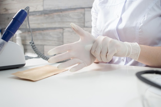 Professional manicurist puts on white medical gloves