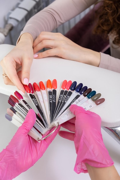 Professional manicurist showing colorful nail polish to check the finish result