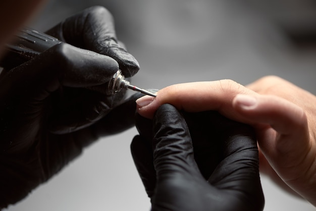 Professional master manicurist working on client fingernails