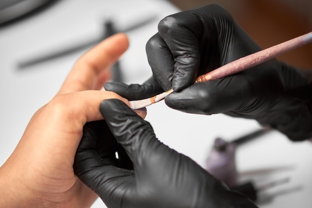 Professional master manicurist working on client fingernails