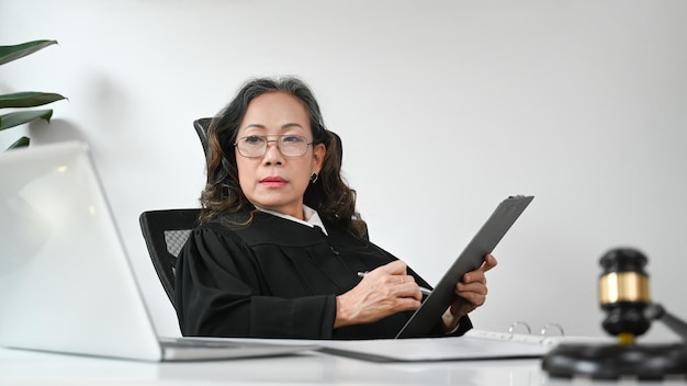 Professional mature female lawyer signing document and using laptop at her workplace Lawyer justice and law attorney concept