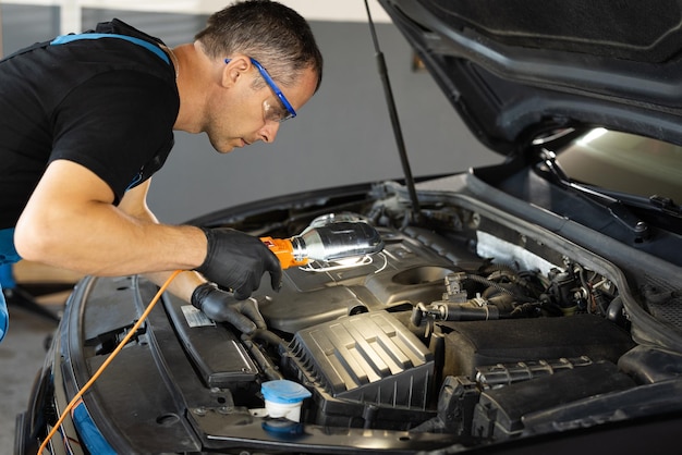 Professional mechanic in blue overalls is working on a car in a car service repairman