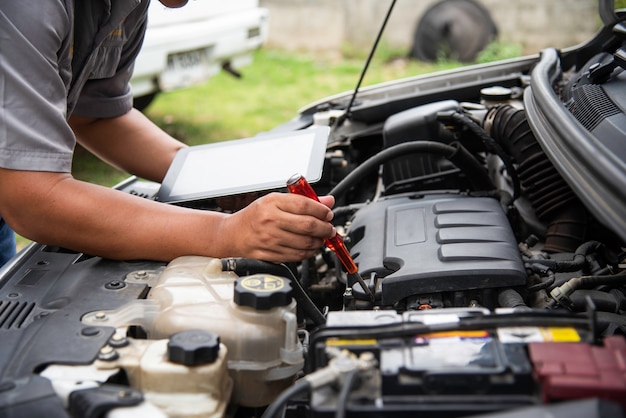 Professional mechanic checking car engine search for data with tablet