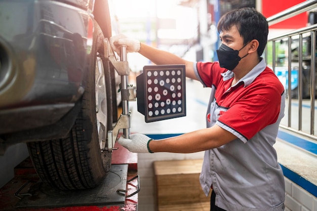 Professional mechanic near wheel center wheel alignment mounted on each tire for driving center Wheel alignment in the garage