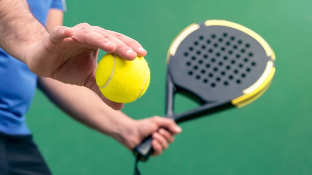 Professional monitor of padel holding black racket on green court Game concept