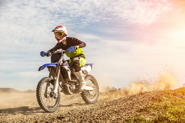 Professional Motocross Motorcycle Rider Drives Through Smoke and Mist Over the Dirt Road Track.