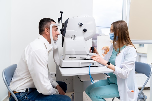 Professional nurse in uniform working with patient. Young beauty doctor in medical mask looking for results.