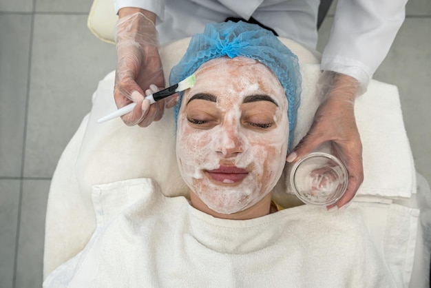 Professional performs ultrasonic cleaning of the skin of the face with the help of a device