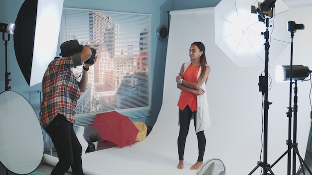 Professional photographer asking model to change poses while make a photo shoot in studio