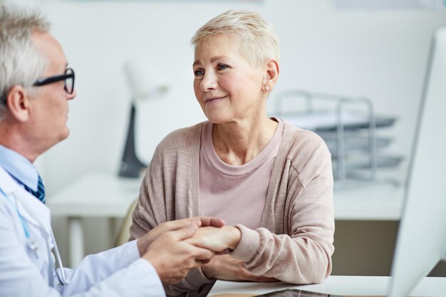 Professional practitioner touching hands of patient